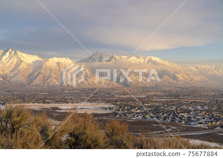 Houses beneath scenic Mount Timpanogos with cloudy blue sky overhead in winter 75677884