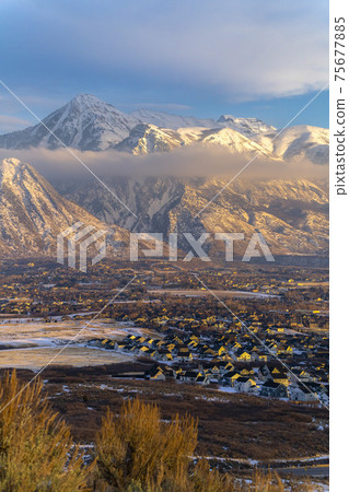 Snowy Mount Timpanogos and charming homes against cloudy blue sky at sunset Snowy Mount Timpanogos and charming homes against cloudy blue sky at sunset 75677885