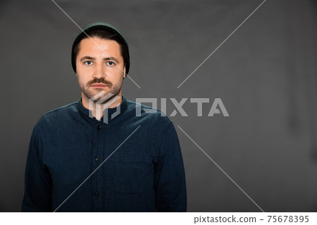 unshaven wimp wobbly guy in knitted cap posing on gray studio backdrop 75678395