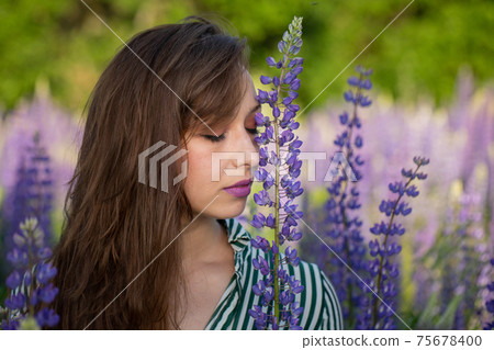 beautiful girl eyes closed Leans Head Against Lupin flower on blooming meadow beautiful girl eyes closed Leans Head Against Lupin flower on blooming meadow 75678400