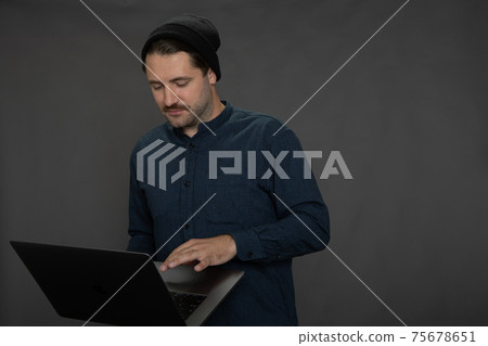 Handsome mustached unshaven guy in knitted cap Communicating in social networks Handsome mustached unshaven guy in knitted cap Communicating in social networks 75678651