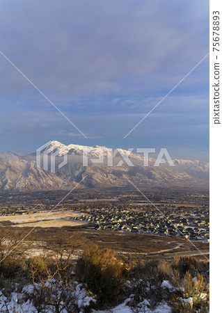 Hilly terrain and residential area against Mount Timpanogos and cloudy sky Hilly terrain and residential area against Mount Timpanogos and cloudy sky 75678893