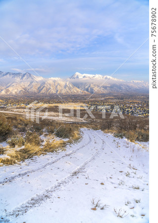 Dirt road on hilly terrain with residences and Mount Timpanogos view in winter Dirt road on hilly terrain with residences and Mount Timpanogos view in winter 75678902