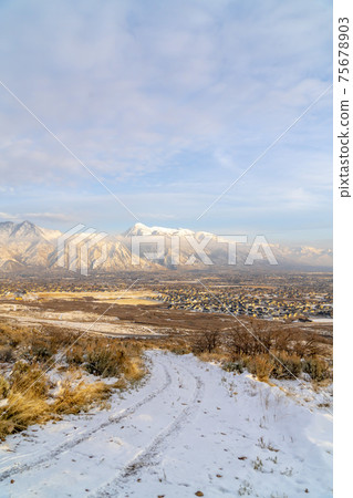 Snowy dirt road on hill with views of neighborhood houses and Mount Timpanogos Snowy dirt road on hill with views of neighborhood houses and Mount Timpanogos 75678903