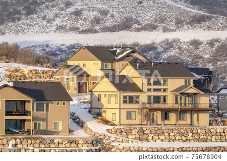 Lovely homes on hilly neighborhood terrain amid natural snowy scenery in winter Lovely homes on hilly neighborhood terrain amid natural snowy scenery in winter 75678904