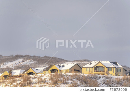 Homes on residential area nestled on top of hills with snow in winter 75678906