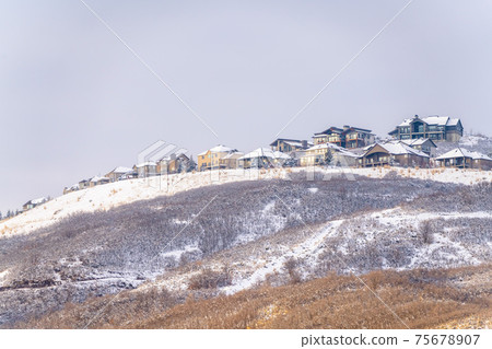 Hill scenery with homes built on top of snow covered slopes against cloudy sky Hill scenery with homes built on top of snow covered slopes against cloudy sky 75678907