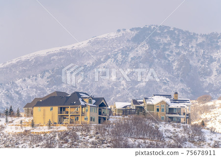 Hilly residential terrain with charming homes and snowy natural beauty 75678911