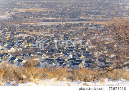 Neighborhood landscape nestled amid hilly terrain blanketed with snow in winter Neighborhood landscape nestled amid hilly terrain blanketed with snow in winter 75678918