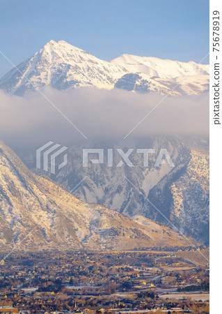 Mount Timpanogos on a cold winter day against blue sky with homes in the valley 75678919