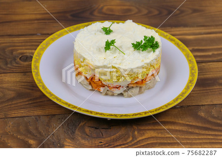 Tasty layered salad with chicken, carrot, eggs, cheese and mayonnaise on wooden table 75682287