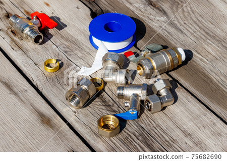 Various plumbing spare parts and sealing tape on rustic wooden background 75682690