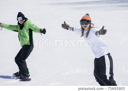 年輕的男人和女人在滑雪板上的斜坡上滑雪 75685805