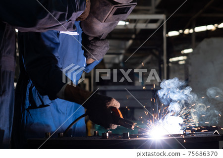 Skillful metal worker working with arc welding machine in factory Skillful metal worker working with arc welding machine in factory 75686370