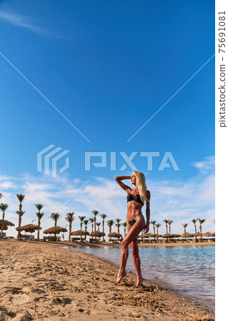 Young fashion woman standing in water on the beach 75691081