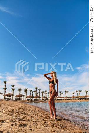 Young fashion woman standing in water on the beach 75691083