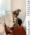 Doctor holding syringe and using cotton disk making injection to patient in medical mask. 75692298