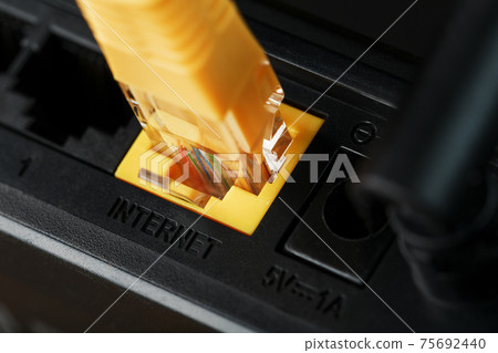 A yellow patch cord is inserted into the Wi-Fi port of the router to access the Internet. 75692440