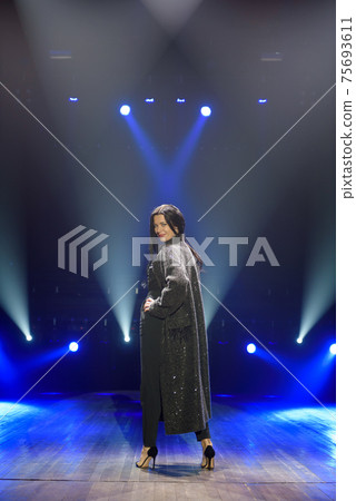 Beauty woman artist on the stage. Dark background, smoke, blue spotlights. 75693611