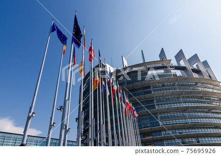 Strasbourg, France. August 2019.The entrance to the modern seat of the European parliament. A row of flagpoles with the flags of the member states of the European Union welcomes those who enter. Strasbourg, France. August 2019.The entrance to the modern seat of the European parliament. A row of flagpoles with the flags of the member states of the European Union welcomes those who enter. 75695926