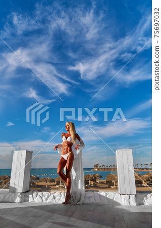 The young woman in white pareo on a terrace and blue sky on a background 75697032