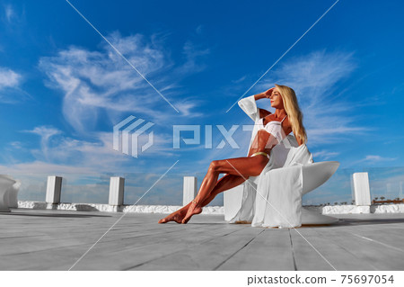 The young woman in white pareo on a terrace and blue sky on a background 75697054