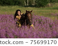 Beautiful woman with long hair in yellow dress riding bareback a brown horse in among purple flowers in green field 75699170