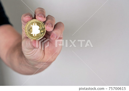 Hand holds coin with bitcoin symbol image Hand holds coin with bitcoin symbol image 75700615