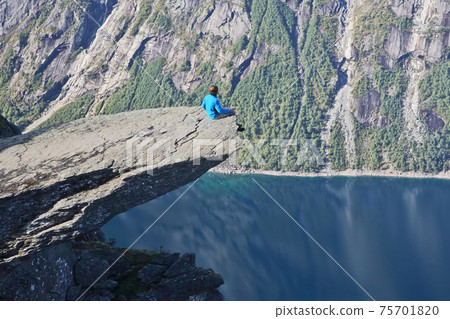 the man sits on the tip of the Troll's tongue. Norway 75701820