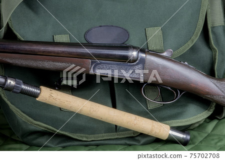 Old Shotgun with Fishing Rod and Game Bag on an Outdoor Coat 75702708