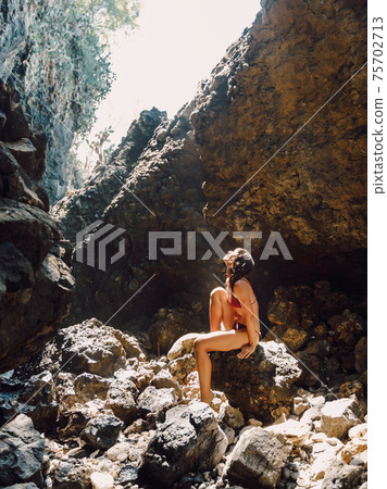 Slim brunette woman in bikini posing at sandy beach. Tanned female model at vacations 75702713