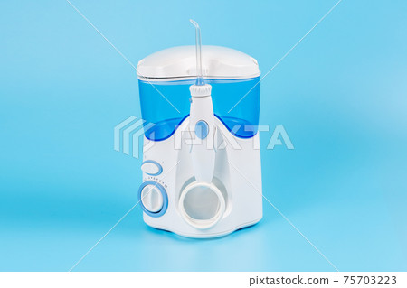 Electronic Tooth Irrigator for personal home usage on blue background. Electronic Tooth Irrigator for personal home usage on blue background. 75703223