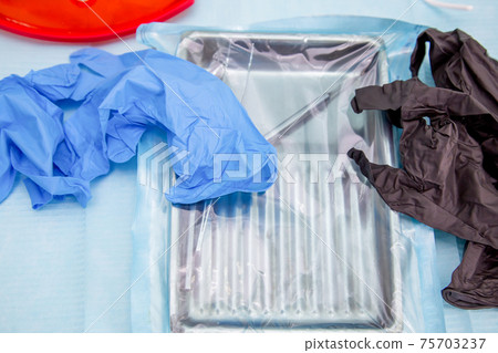 Sterile medical instruments in packaging and blue and black disposable gloves Sterile medical instruments in packaging and blue and black disposable gloves 75703237