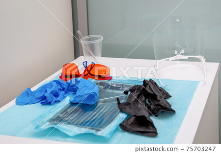 Sterile medical instruments in packaging and blue and black disposable gloves Sterile medical instruments in packaging and blue and black disposable gloves 75703247