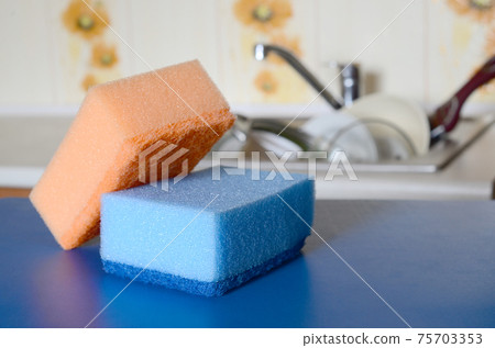 A few sponges lie on the background of the sink with dirty dishes 75703353