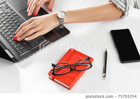 Woman with red manicure work with laptop on white table. Business lady work from home 75703354