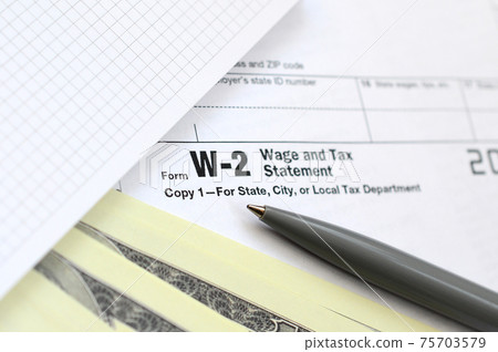 The pen, notebook and dollar bills is lies on the tax form W-2 Wage and Tax Statement. The time to pay taxes The pen, notebook and dollar bills is lies on the tax form W-2 Wage and Tax Statement. The time to pay taxes 75703579