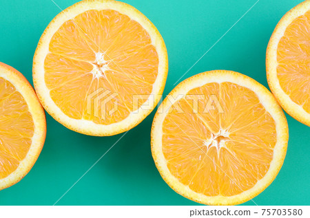 Top view of a several orange fruit slices on bright background in turquoise green color. A saturated citrus texture image Top view of a several orange fruit slices on bright background in turquoise green color. A saturated citrus texture image 75703580