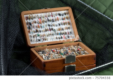 Wooden Fly Box with Trout Flies and Landing Net on an Outdoor Coat Wooden Fly Box with Trout Flies and Landing Net on an Outdoor Coat 75704338