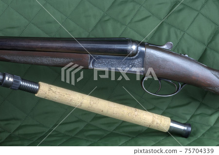 Vintage Shotgun with Fishing Rod on an Outdoor Coat Vintage Shotgun with Fishing Rod on an Outdoor Coat 75704339