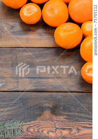 A lot of fresh orange mandarins lie on a brown wooden background A lot of fresh orange mandarins lie on a brown wooden background 75705112