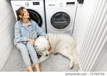 Woman with a dog in the laundry at home Woman with a dog in the laundry at home 75706709