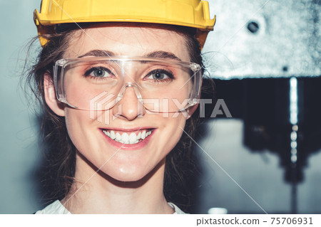 Young woman factory worker close up portrait in manufacturing job factory Young woman factory worker close up portrait in manufacturing job factory 75706931