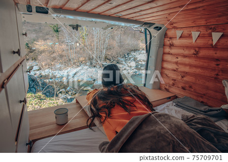 Vanlife - Young woman lying in camping van and looking at beautiful nature Vanlife - Young woman lying in camping van and looking at beautiful nature 75709701