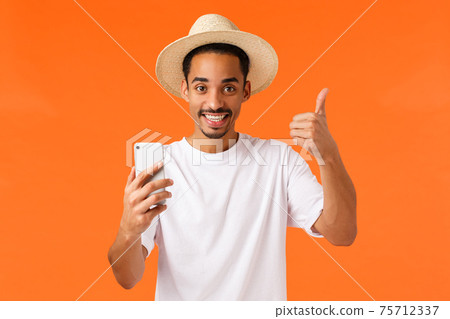 Nice thanks. Happy african-american male tourist asked hotel manager give wifi password to contact family via video-call, show thumbs-up, relaxing during vacation, summer resort, orange background 75712337