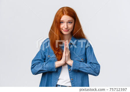 Waist-up portrait cute and silly redhead girl looking hopeful and wishful camera, asking for something, have favour to ask, press hands together chest, praying smiling and glancing in plead 75712397