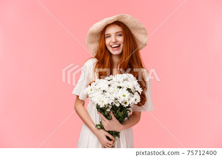 Excited joyful charismatic redhead woman having perfect date, feeling happy and carefree, holding bouquet white flowers and laughing cheerful, wearing sun hat, standing pink background Excited joyful charismatic redhead woman having perfect date, feeling happy and carefree, holding bouquet white flowers and laughing cheerful, wearing sun hat, standing pink background 75712400