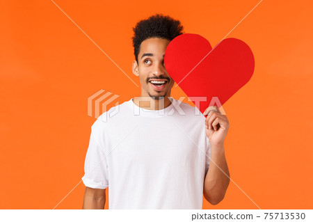 Dreamy handsome african-american guy found true love, giving valentines card to lover, looking upbeat up thoughtful, imaging perfect date, express own love and affection, standing orange background Dreamy handsome african-american guy found true love, giving valentines card to lover, looking upbeat up thoughtful, imaging perfect date, express own love and affection, standing orange background 75713530
