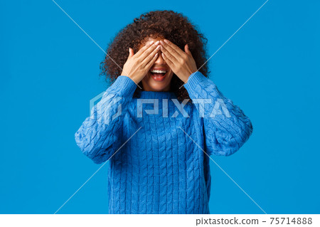 Girl playing with siblings in hide-n-seek, counting ten start seeking. Charismatic lovely african american woman close eyes as waiting surprise or make peekaboo gesture, blue background 75714888