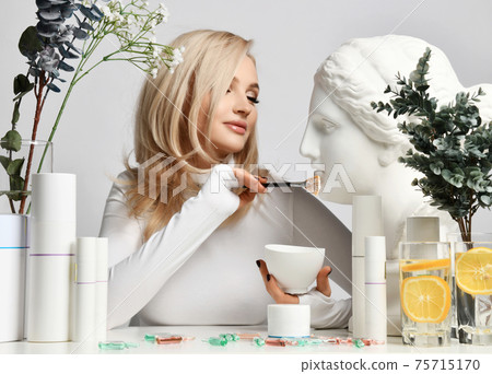 Blonde woman healthy silky skin sits at table with Blonde woman healthy silky skin sits at table with 75715170